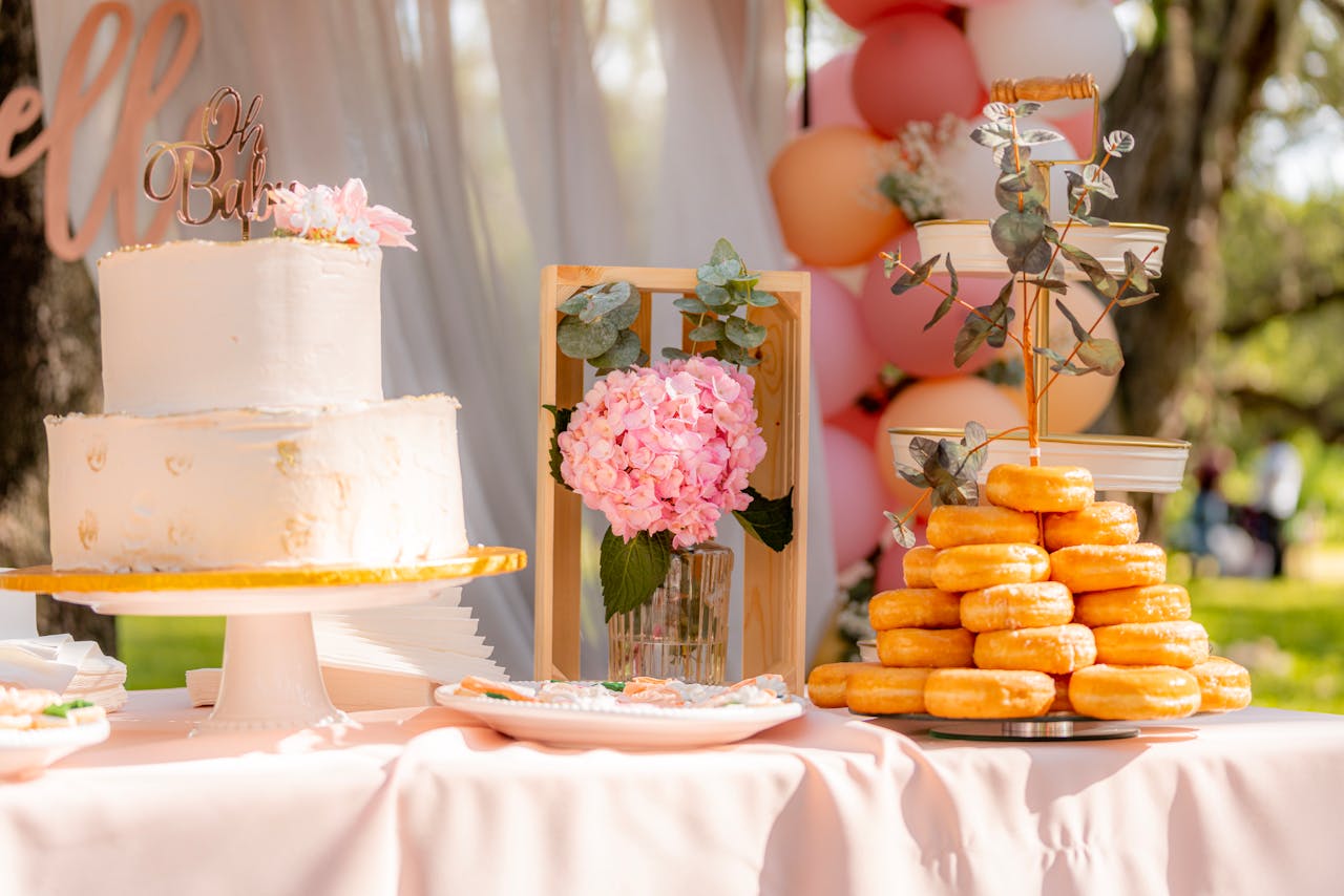 services-01 A beautifully decorated outdoor dessert table set for a baby shower featuring a cake and donuts.